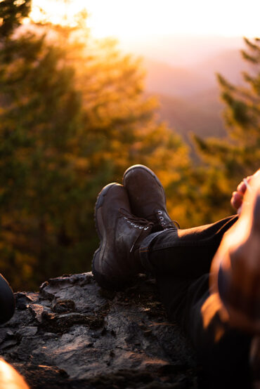 A close-up image of hiking boots on a hiker as they rest on. mountaintop.