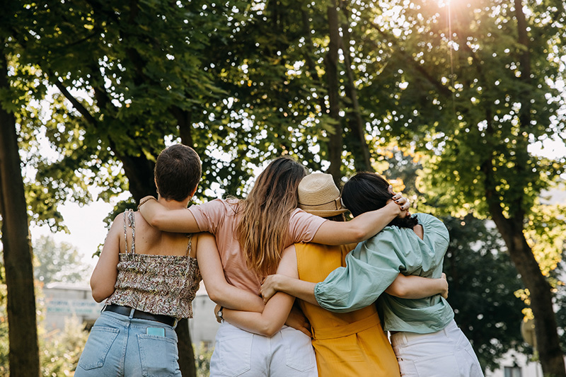 A group of friends face away from the camera towards the woods of Vermont.