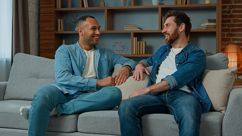 Two friends talk on a couch while participating in an addiction treatment program.