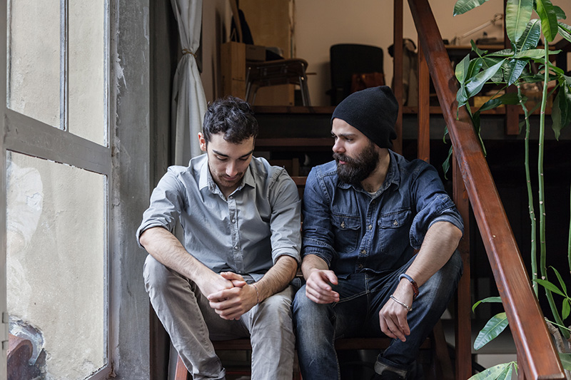 Two men talk while sitting on the stairs.